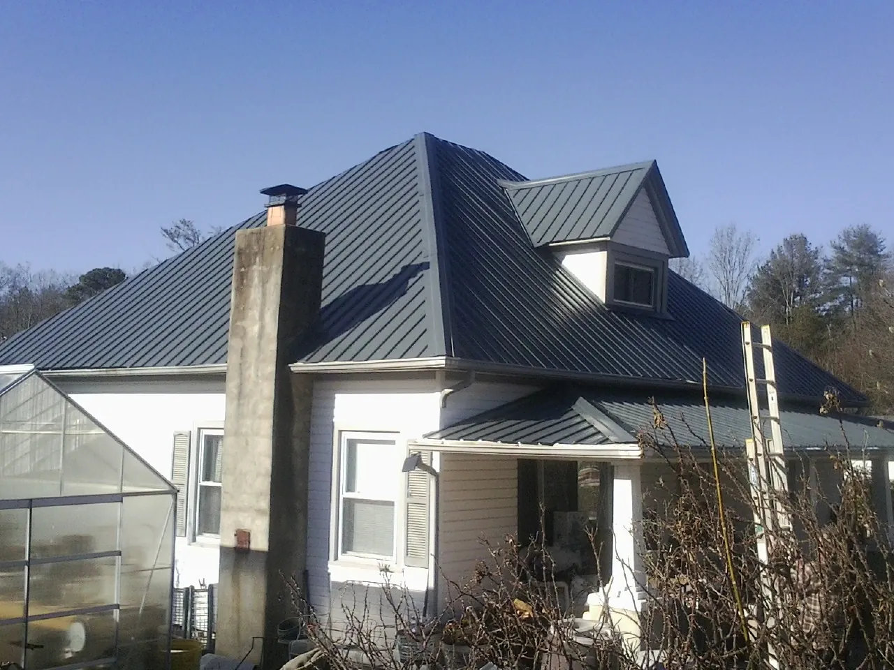 Dark blue standing seam metal roof on a white farmhouse with dormer — Slate & Tile Roof Repair by Roofing Brothers in Leonardsville