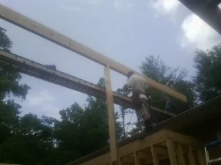 Carpenter setting a ridge beam over a new addition frame — Ice Dam Removal by Roofing Brothers in Leonardsville