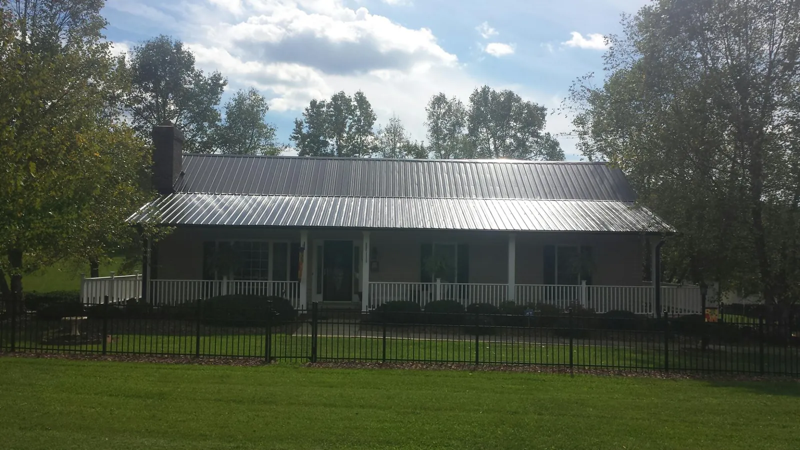 Gray metal roof on a brick ranch with a full width front porch — Gutter Guard Installation work by our crew in Leonardsville