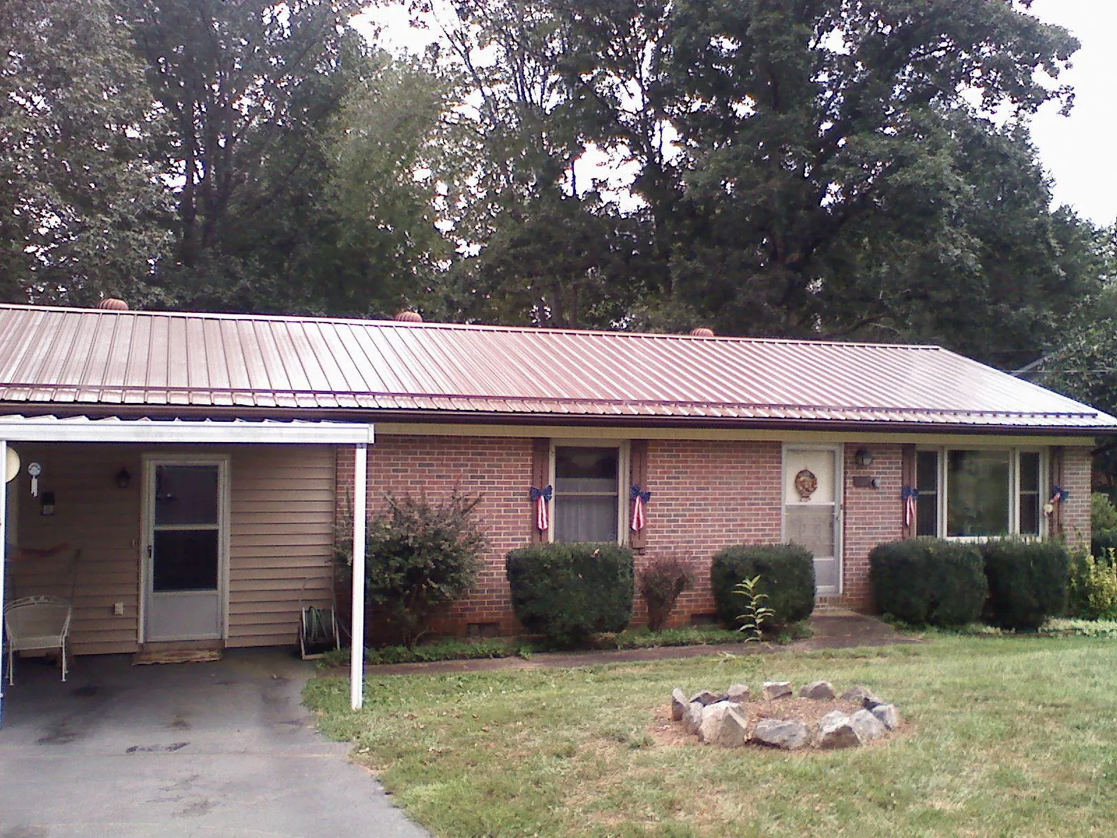 Bronze metal roof and carport on a brick ranch home — Roof Repair work by our crew in Leonardsville