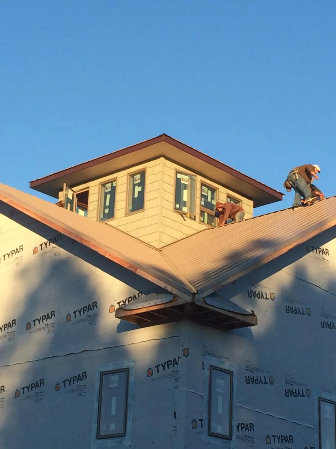 Roofers working around a rooftop cupola on a new metal roof at sunset — Roof Waterproofing in Leonardsville by Roofing Brothers